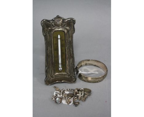 AN EDWARDIAN SILVER MOUNTED BRASS THERMOMETER, silver bangle and a silver charm bracelet (3)