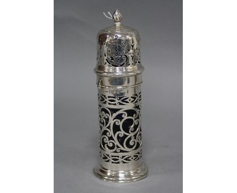 AN EDWARDIAN SILVER CASTOR OF CYLINDRICAL FORM, flame finial on a bayonet fitting pull off cover, the base with foliate scrol
