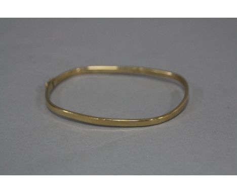 A LATE 20TH CENTURY 9CT GOLD BANGLE, 'TV' shape, half engraved in diamond cut border, measuring approximately 64mm x 54mm, by