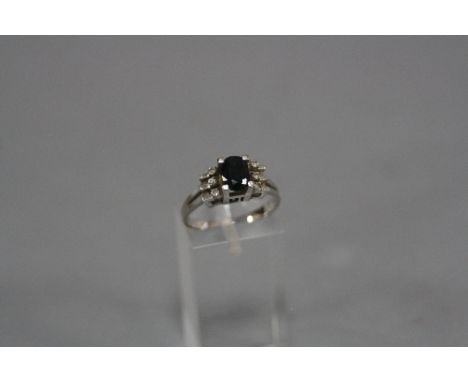 A MODERN SAPPHIRE AND DIAMOND DRESS RING, one oval dark blue mixed cut sapphire measuring approximately 7mm x 5mm estimated w