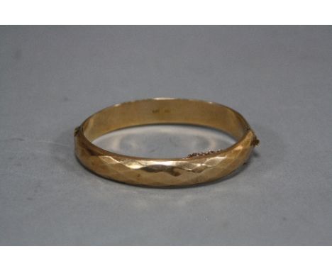 A LATE 20TH CENTURY OVAL HINGED BANGLE, diamond cut design, measuring approximately 68mm x 60mm by a width of 10.5mm, stamped