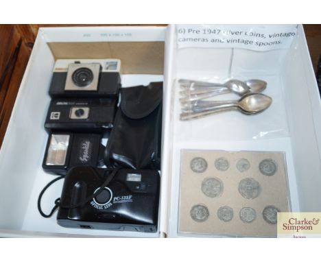 A box containing pre 1947 silver coinage; a vintage camera and spoons