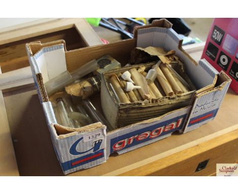 A cardboard tray box containing a quantity of small glass test tubes, ceramic filters, and other scientific measures and cont