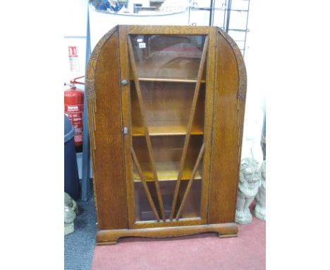 An Art Deco Oak Display Cabinet, with applied floral carved shoulders and sunburst glazed door, 93cm wide.