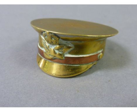 An early 20th century brass snuff box, in the form of a military cap  