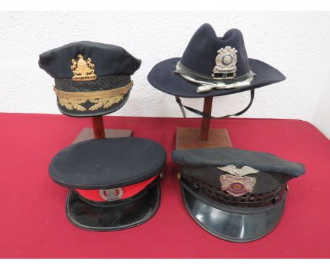 Four Various Foreign Police Hatsconsisting dark blue Police stetson with silvered cord band.  Chrome and enamel New Hampshire