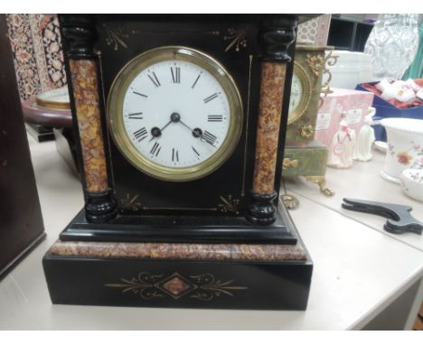 A Victorian black marble mantel clock having circular Roman numeral dial and striking movement, flanked by rouge marble colum