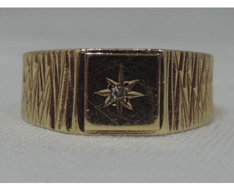 A gents 9ct gold signet ring having a diamond chip insert in a star mount to bark effect shoulders, approx 4.4g &amp; size R