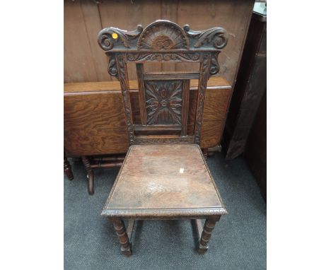 A Victorian oak hall chair having carved crest and foliate back, with solid seat and bobbin legs
