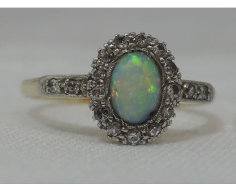 A lady's dress ring having an opal and diamond cluster with diamond set shoulders on a yellow metal loop stamped plat 18ct, s