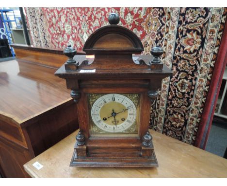 A early 20th century oak cased mantel clock having crest and spindle top over spandrel Roman numeral dial with striking movem