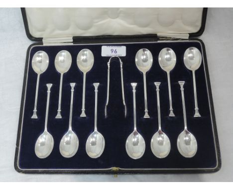 A cased set of twelve silver teaspoons with matching sugar nips, all having architectural detail to terminals, London 1921, J
