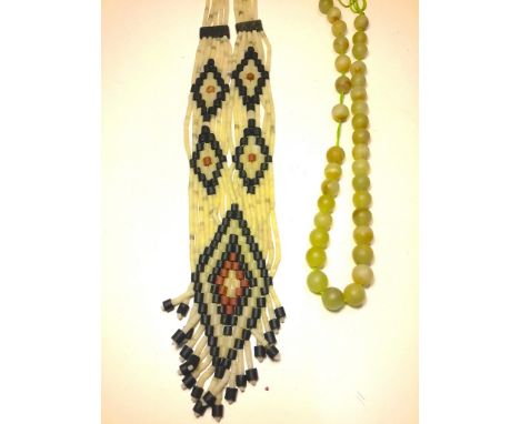 A jade tribal design necklace with a thread of jade beads.