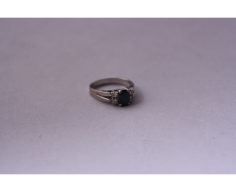 A FOUR DIAMOND AND CENTRAL SAPPHIRE RING, unmarked white metal, ring size M