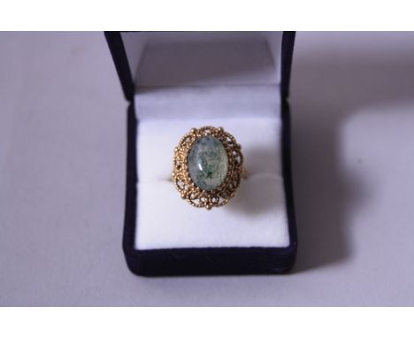 AN ADVENTURINE QUARTZ DRESS RING, with cabachon stone and fancy scalloped surround to the bi-pronged tapered band, stamped 9c