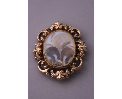 A MOURNING BROOCH,  hair behind glass with scalloped surround, engraved to reverse 'E. Harper'