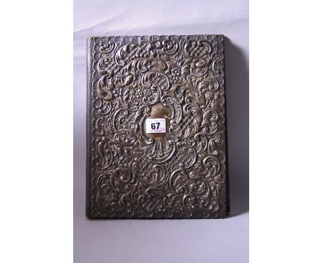 A SILVER MOUNTED PAPER FILE, the rectangular frontispiece having shaped rim to embossed scroll and floral decoration, vacant 