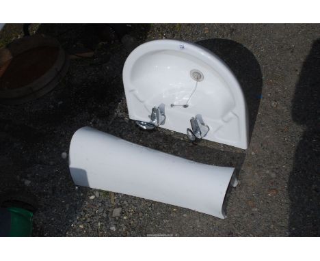 A hand basin and pedestal with taps.