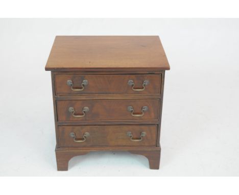 A Georgian style mahogany chest of small proportionsThe rectangular top above three cockbeaded drawers, brass swan neck handl