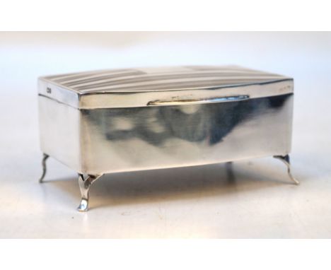 An Art Deco silver jewellery boxOf shaped rectangular form, with engine turned decoration, vacant cartouche, raised on four f
