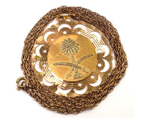 A Saudi Arabian emblem medallion pendantTo a pierced scalloped border, yellow metal stamped 750, to an unmarked yellow metal 