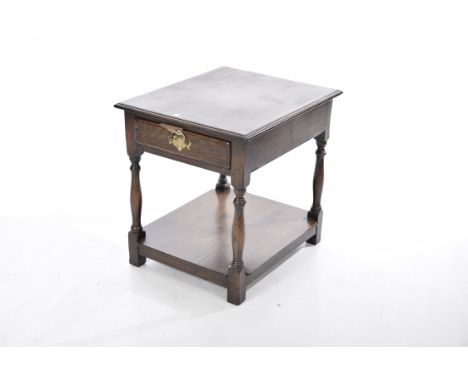 A reproduction oak lamp table The rectangular moulded top above a single frieze drawer with brass swan neck handles raised on