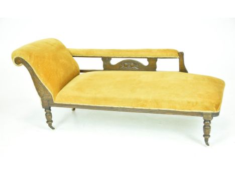 A Victorian oak and upholstered chaise longueWith a padded scroll end and padded rail raised on a shaped splat over a sprung 