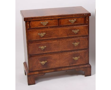 A walnut bachelors chest, in the early 18th century style, having feather banded fold-over top above two short and three long