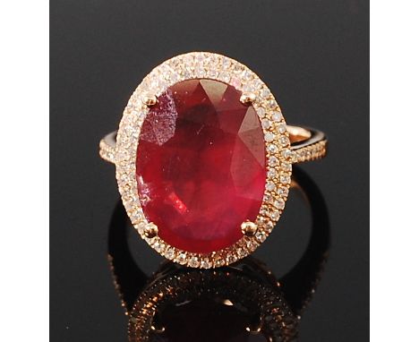 A 14ct gold, ruby and diamond set dress ring, the large four claw set oval cut ruby weighing approx 10.5ct, in a two tier sur