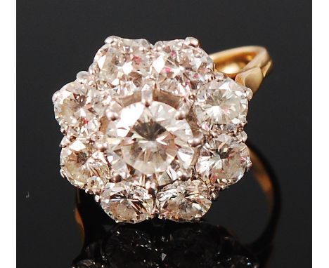 An 18ct gold diamond flower head cluster ring, arranged as a centre claw set brilliant weighing approx 1.1ct, in a surround o