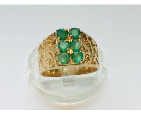 A 9ct yellow gold wide textured dress ring, set with six round emeralds to the centre ring weighs 4.8 grams, finger size L. 