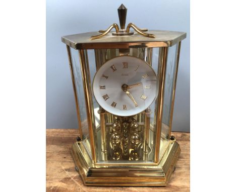 A German brass anniversary clock by Kundo, the dial with gilt Roman numerals, in hexagonal bevelled glass case, raised on ste