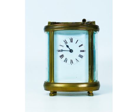 Brass carriage clock of oval form, winds, ticks, runs &amp; sets.  One glass side panel loose, and secured with cellotape.  C