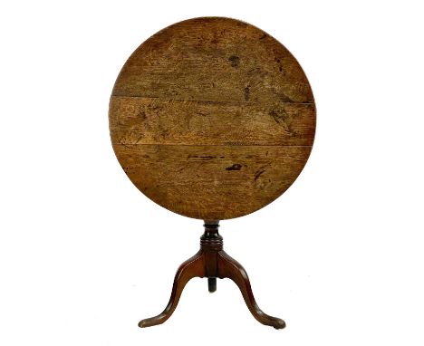 A George III oak circular tripod table. With a tilt top and turned pillar, height 73cm, diameter 74cm.The top has age related