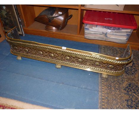 A large Brass fire fender having pierced harp and floral grill with rope effect border, a/f. 54" long x 9" tall.