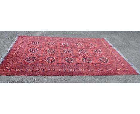 An Afghan handmade wool Khan Mohamadi carpet with repeat floral central motif amidst decorative leaf and geometric pattern bo