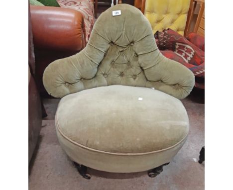 A late Victorian camel back boudoir chair with button back upholstery, set on ebonised legs and casters