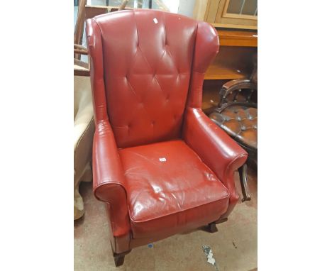 A late 20th Century red button back leather upholstered wing back armchair, set on moulded cabriole front legs - tears and we