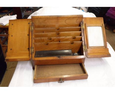 An antique oak stationery box with front opening to reveal an internal letter rack, pen stand and ceramic memo board