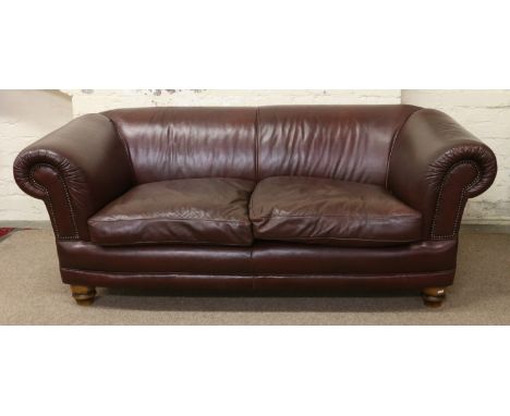 A good quality brown leather two seat sofa raised on turned bun feet.