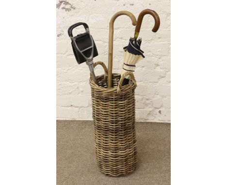 A basketware stickstand to include shooting stick, walking stick and a gentlemens umbrella.