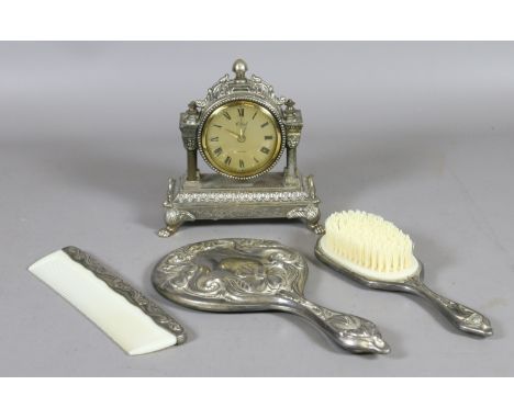 A brass cased alarm clock and a silver plate three part dressing table set.