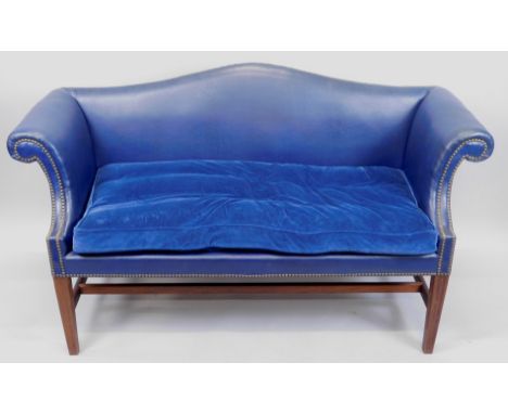 A George III style small mahogany sofa, upholstered in blue leather, with a camel shaped back, studded borders, and a velvet 