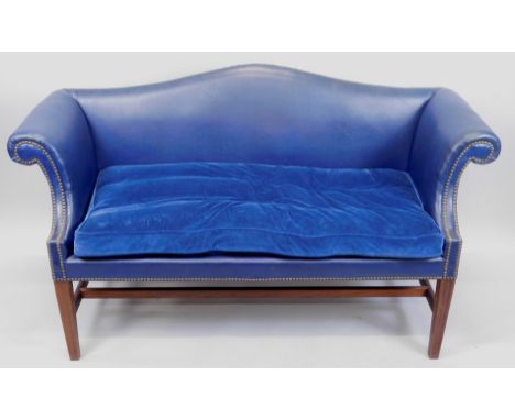 A George III style small mahogany sofa, upholstered in blue leather, with a camel shaped back, studded borders, and a velvet 