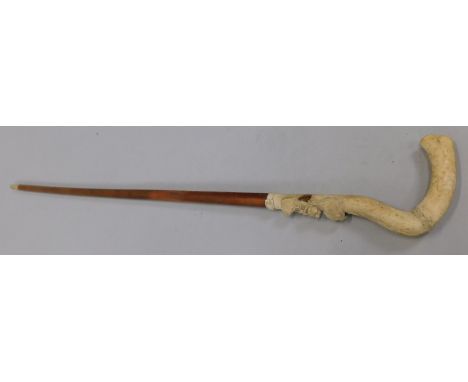 A Victorian malacca walking stick, the ivory handle carved with three dogs holding a rope or lead (M)