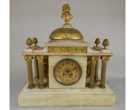 A late 19thC/early 20thC French onyx and gilt metal portico type mantel clock, with a gilt dial, flanked by four reeded corin