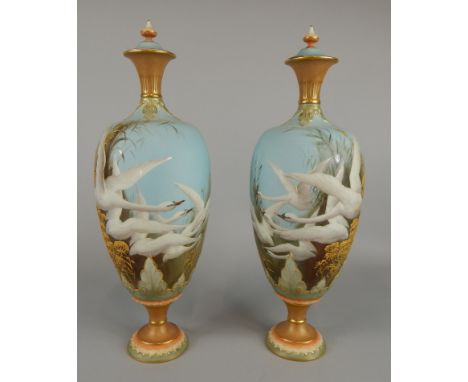 A pair of Royal Worcester vases and covers, of ovoid form painted by Charles Baldwyn with swans in flight on a sky blue groun