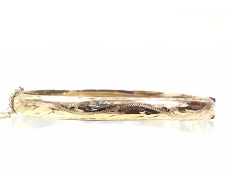 GOLD BANGLE, IN NINE CARAT GOLD with safety chain and engraved decoration, marked for nine carat gold6.5cm wideQty: 8.19g