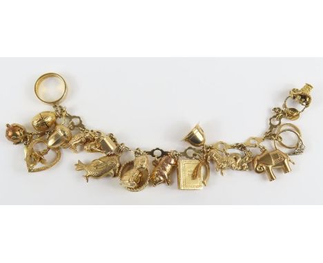 A 9ct gold fancy link bracelet with various charms attached, charms include a 22ct gold wedding band, an egg opening to revea