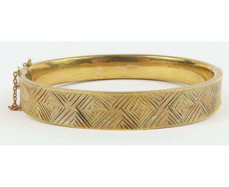 A 9ct gold fully engraved hinged bangle, with safety chain, 6.2cm internal diameter, 15.8g gross